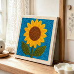 A cheerful sunflower punch needle artwork displayed on a table