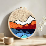 Abstract layered mountain punch needle artwork displayed on a table