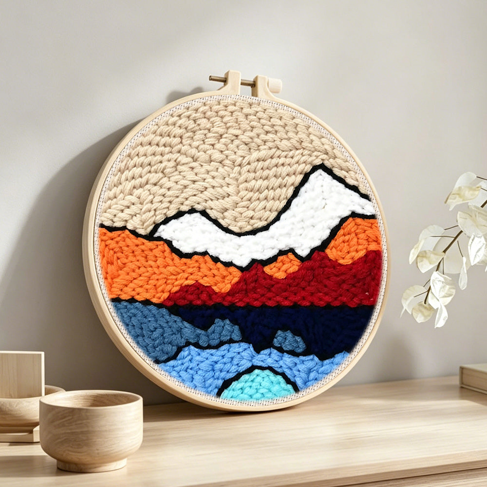 Abstract layered mountain punch needle artwork displayed on a table