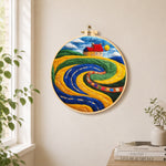 Abstract swirling fields and red roof cottage needle felt wall art displayed in a bright home interior