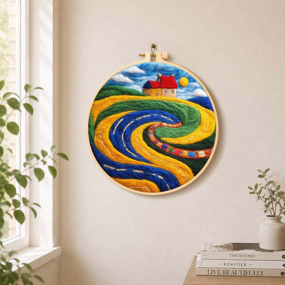 Abstract swirling fields and red roof cottage needle felt wall art displayed in a bright home interior