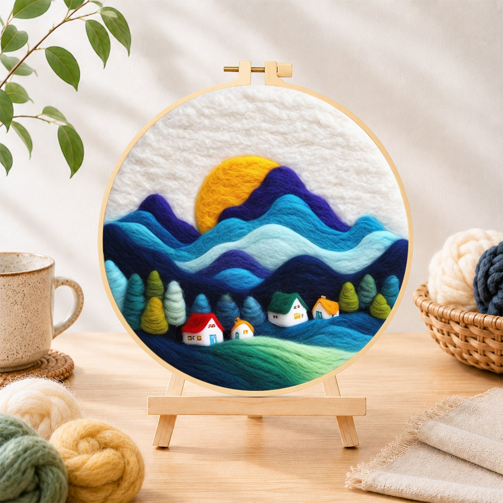 Finished abstract wavy mountains and tiny houses needle felting displayed on a wooden easel