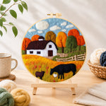 Finished autumn farm scene needle felting displayed on a wooden easel