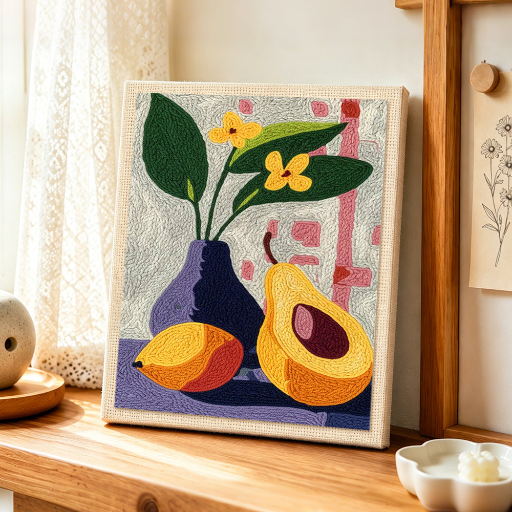 Avocado and flowers still life punch needle artwork displayed on a table