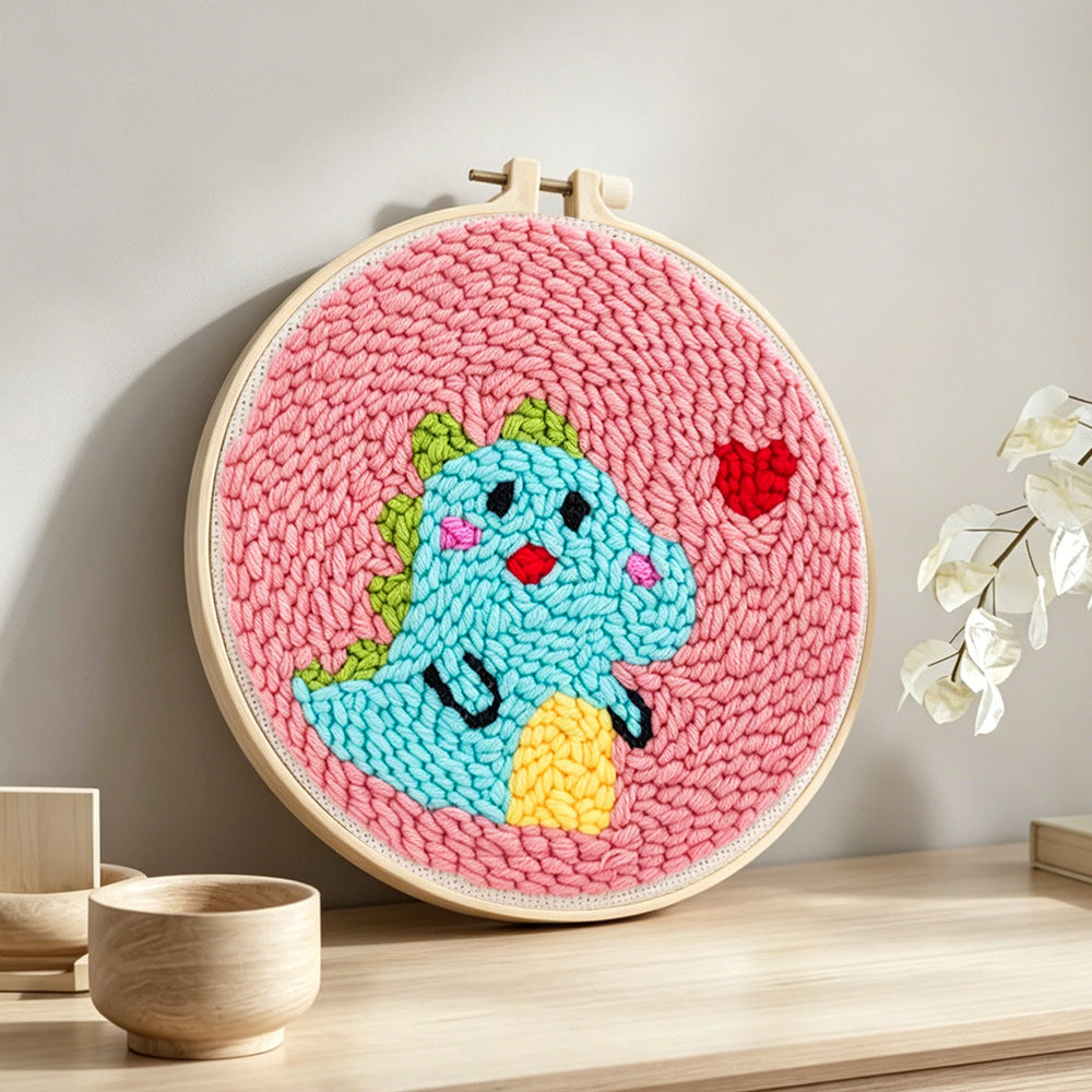 Baby dinosaur and little heart punch needle artwork displayed on a table