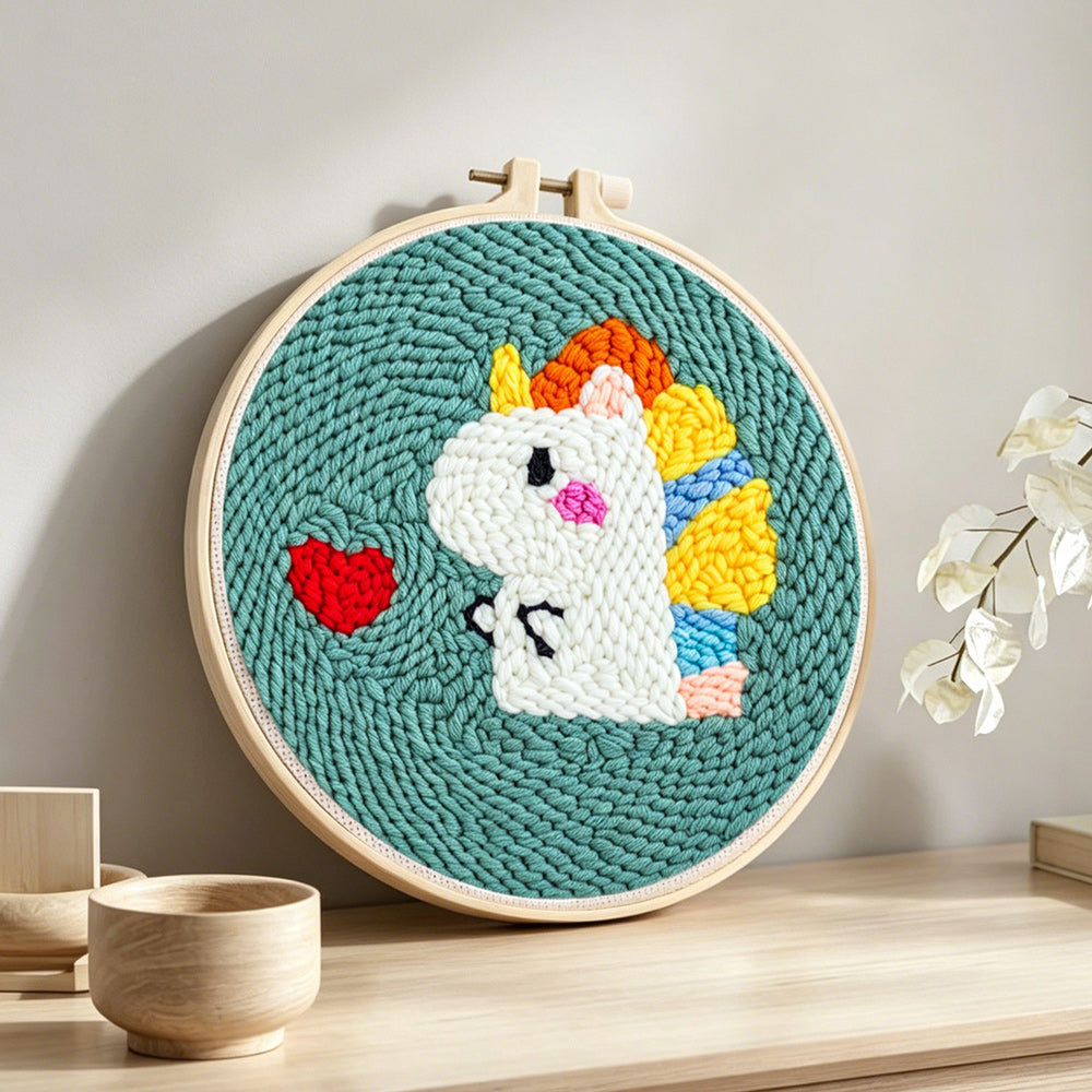 Baby dinosaur and red heart punch needle artwork displayed on a table
