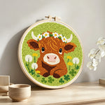 Baby highland cow and dandelions punch needle artwork displayed on a table