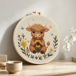 Baby highland cow and sunflower punch needle artwork displayed on a table