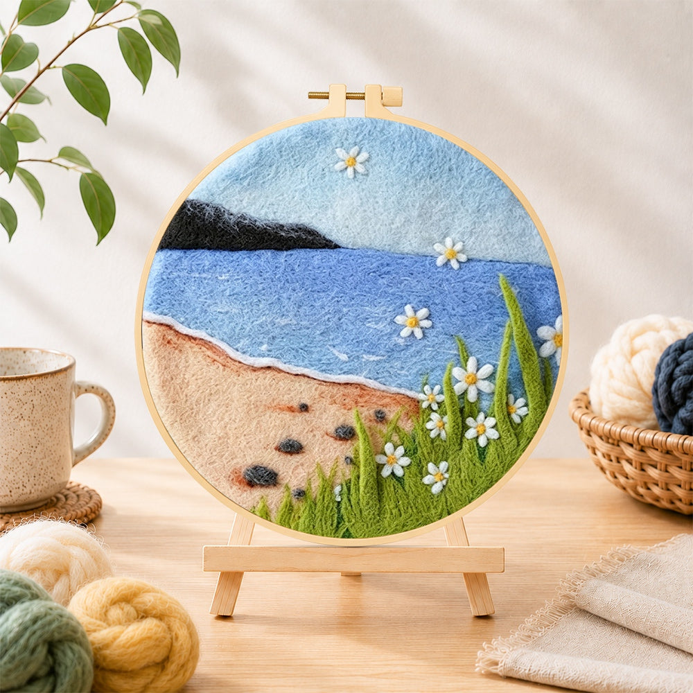 Finished beach daisies and blue sea needle felting displayed on a wooden easel