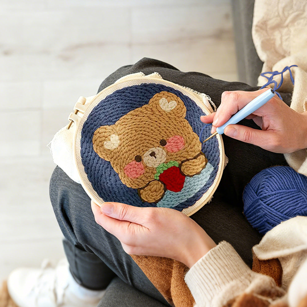 Creating handmade bear holding strawberry punch needle artwork
