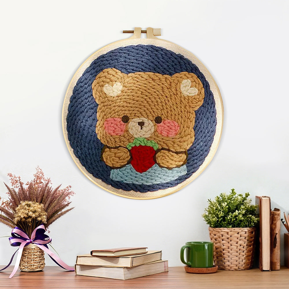 Finished bear holding strawberry artwork displayed on a wall