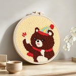 Bear with balloon and party hat punch needle artwork displayed on a table