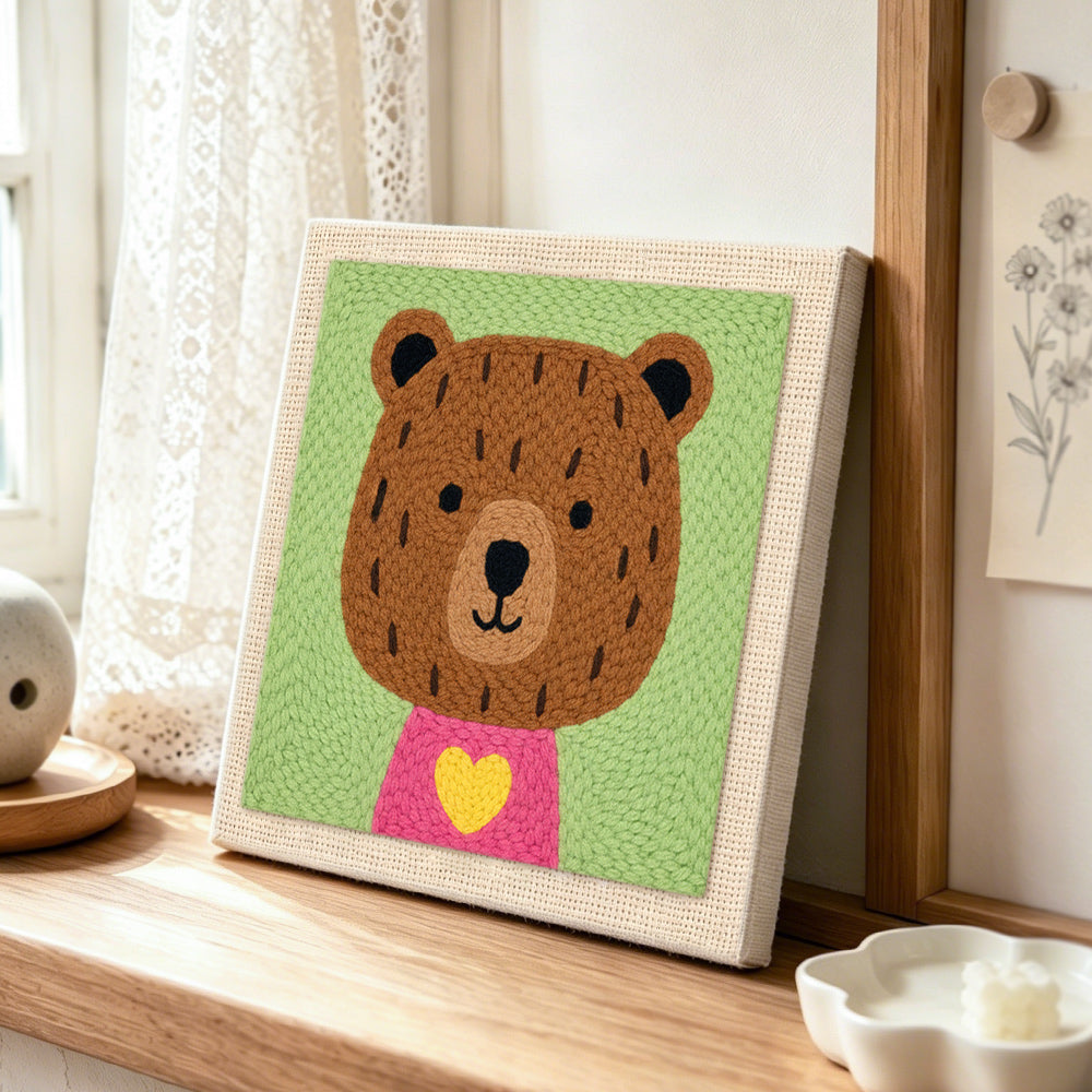 Bear with yellow heart punch needle artwork displayed on a table