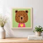 Finished bear with yellow heart artwork displayed on a wall