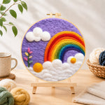Finished beautiful rainbow and white clouds in the purple sky needle felting displayed on a wooden easel
