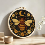 Bee, moon and flowers punch needle artwork displayed on a table