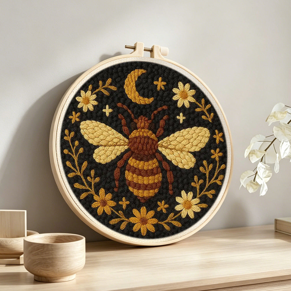 Bee, moon and flowers punch needle artwork displayed on a table