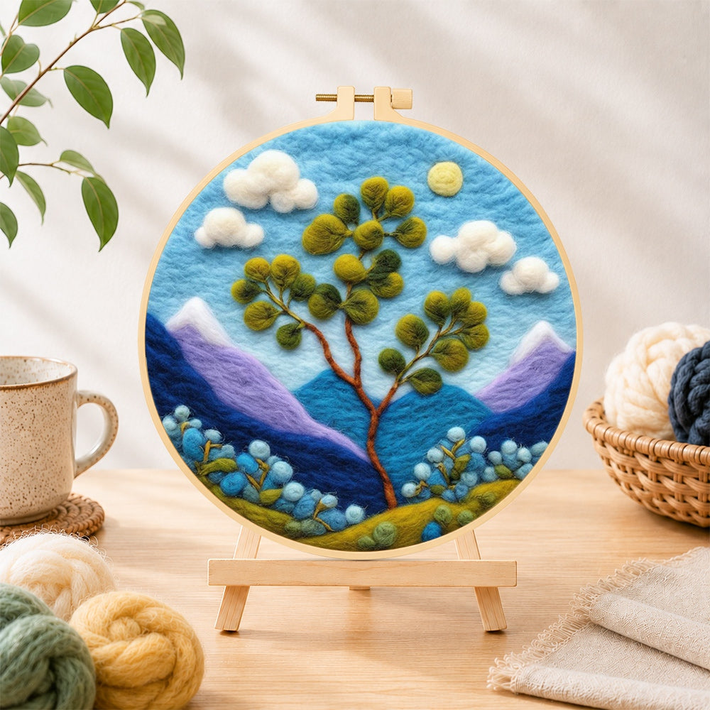 Finished bifurcated tree and mountains needle felting displayed on a wooden easel