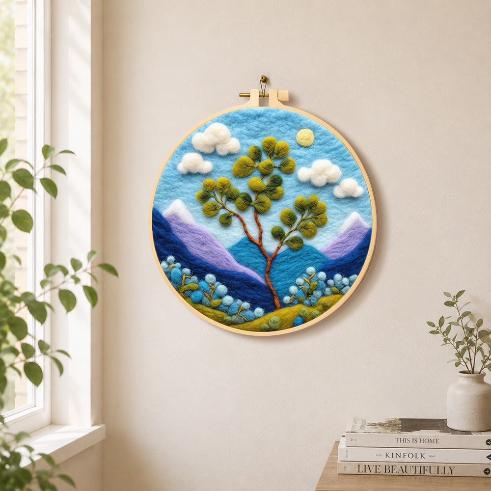 Bifurcated tree and mountains needle felt wall art displayed in a bright home interior