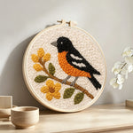 Bird on flowering branch punch needle artwork displayed on a table