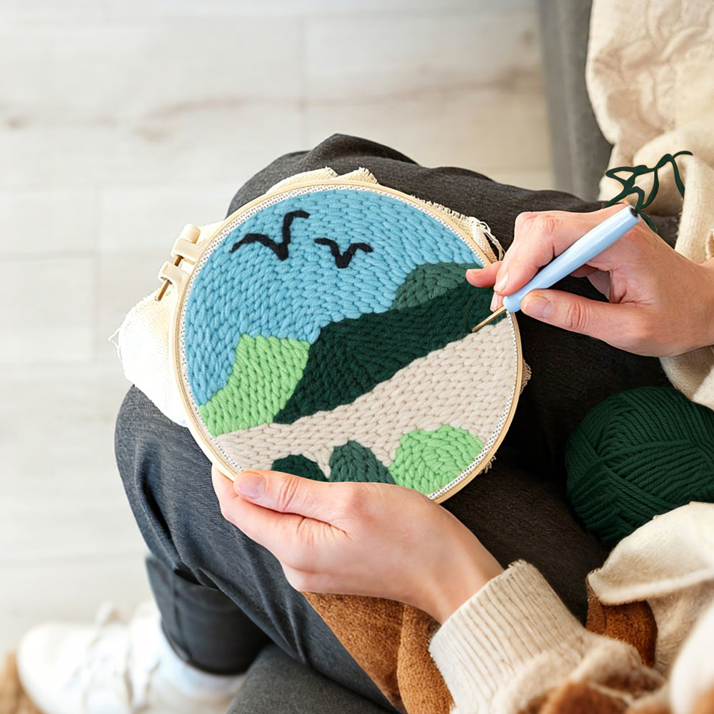 Creating handmade birds over green mountain landscape punch needle artwork