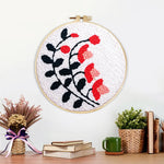 Finished black branches with pink and red blooms artwork displayed on a wall