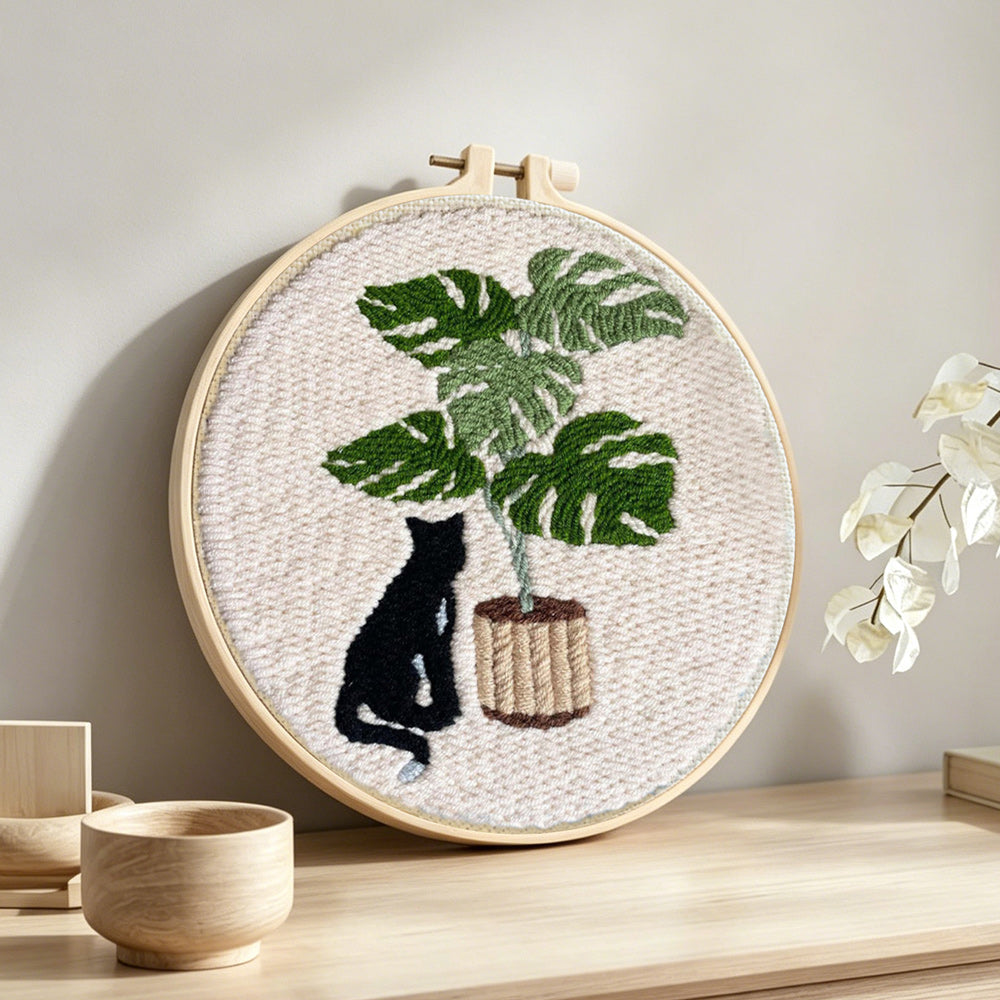 Black cat and monstera plant punch needle artwork displayed on a table