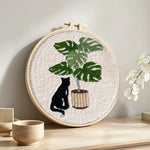 Black cat and monstera plant punch needle artwork displayed on a table