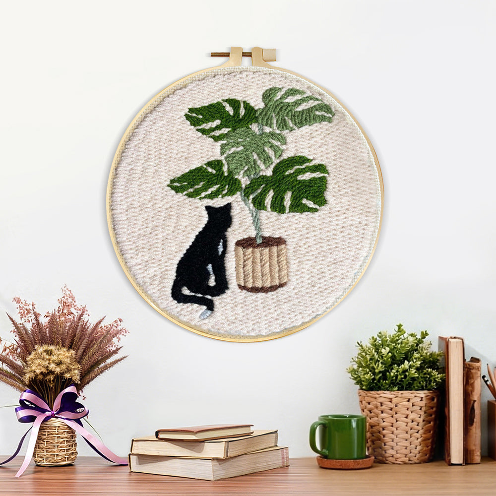 Finished black cat and monstera plant artwork displayed on a wall