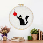 Finished black cat and red ball of yarn artwork displayed on a wall