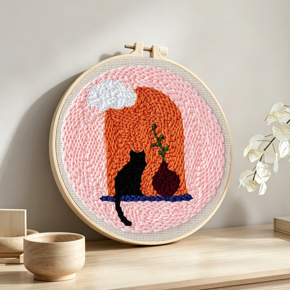 Black cat and terracotta vase punch needle artwork displayed on a table