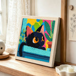 Black cat with colourful abstract leaves punch needle artwork displayed on a table