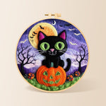 Black cat with green eyes on pumpkin needle felting kit for beginners with a round wooden frame
