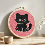Black kitten punch needle artwork displayed on a table