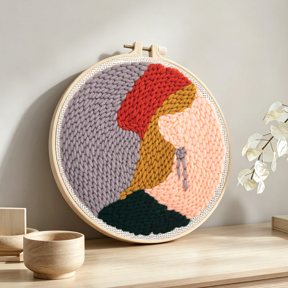 Blonde woman in red hat punch needle artwork displayed on a table