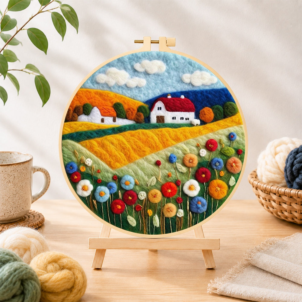 Finished blooming flower field and red roof cottage needle felting displayed on a wooden easel
