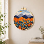Blooming orange roses and mountains needle felt wall art displayed in a bright home interior