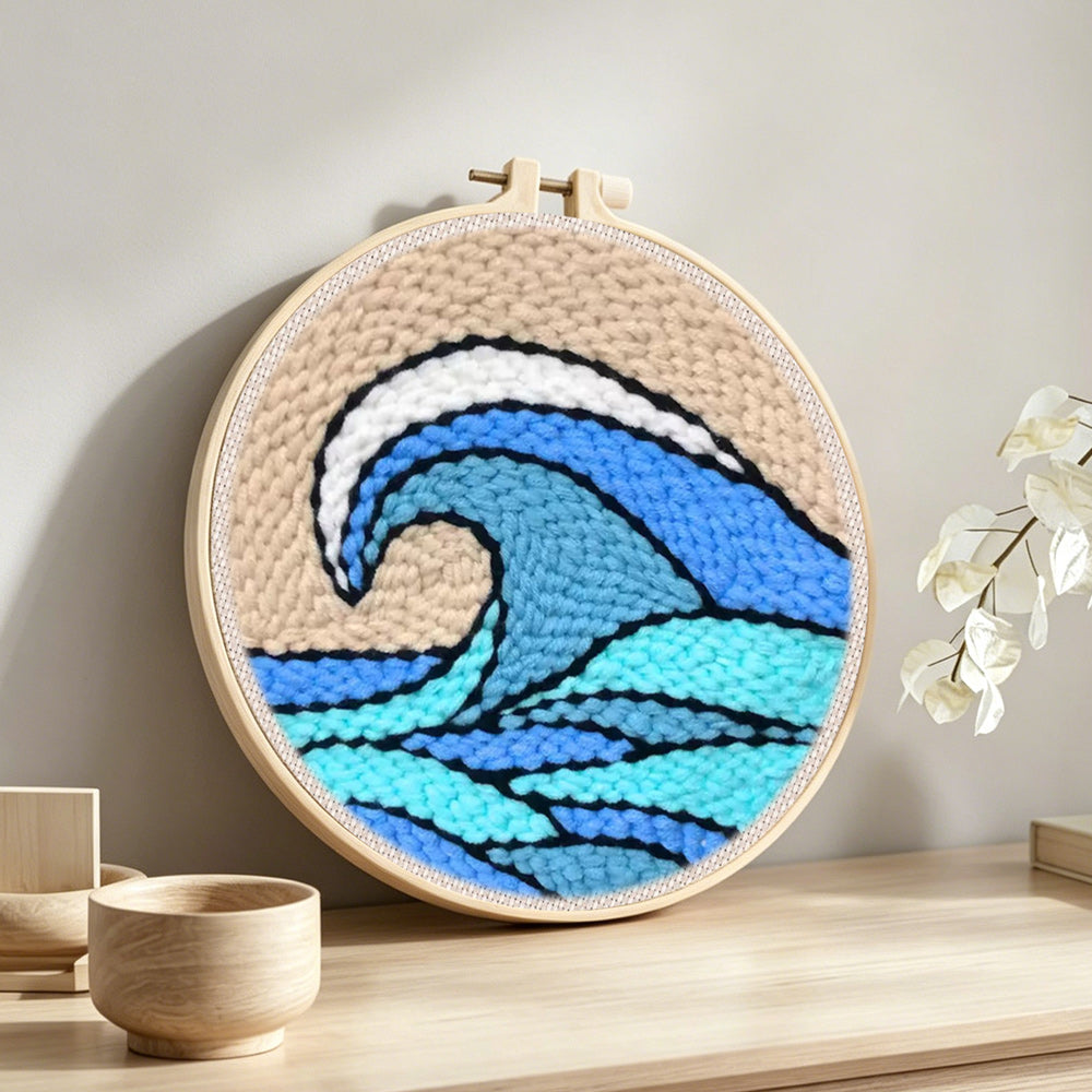Blue and teal rolling wave with beige sky punch needle artwork displayed on a table