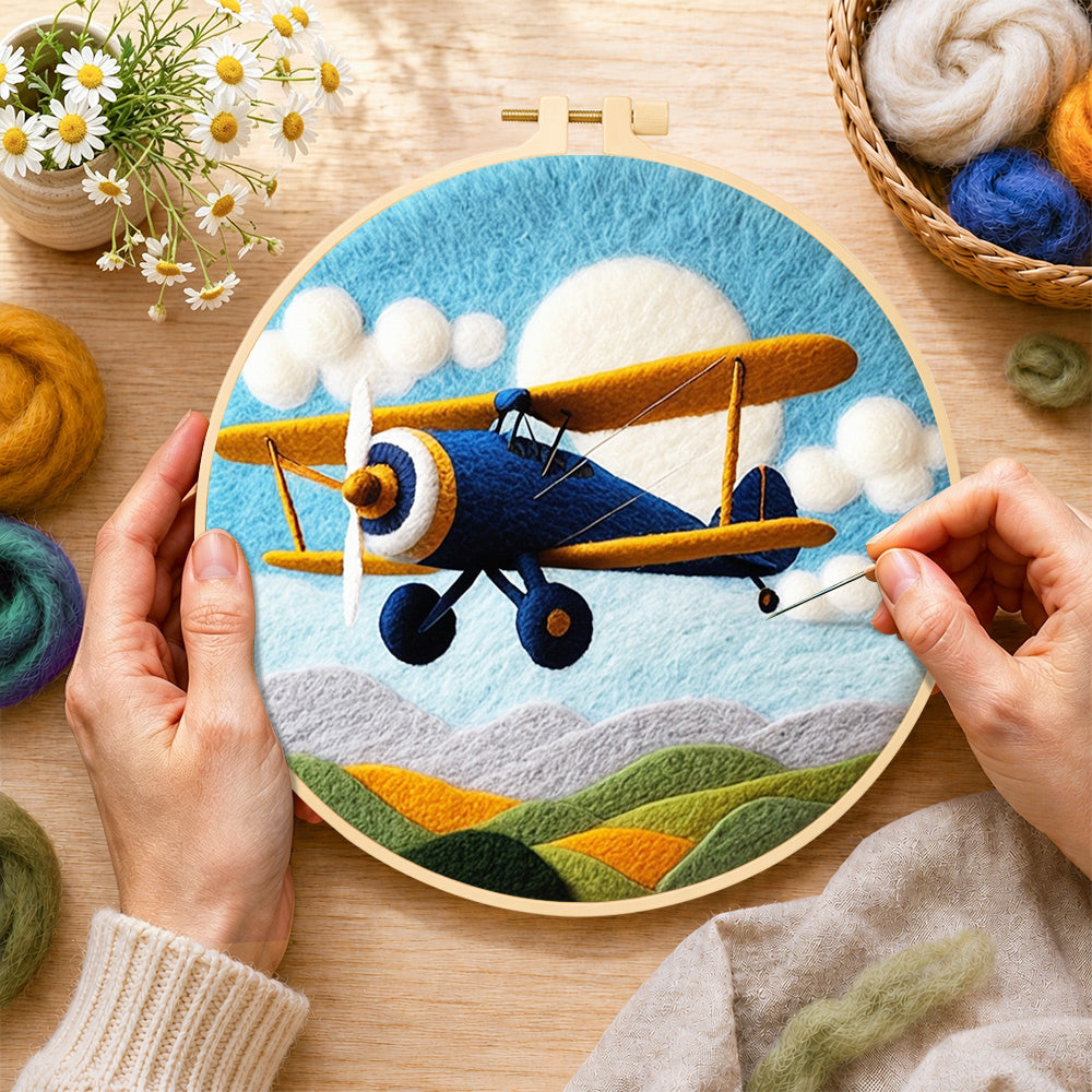 Creating the blue biplane flying wool painting by hand with a felting needle