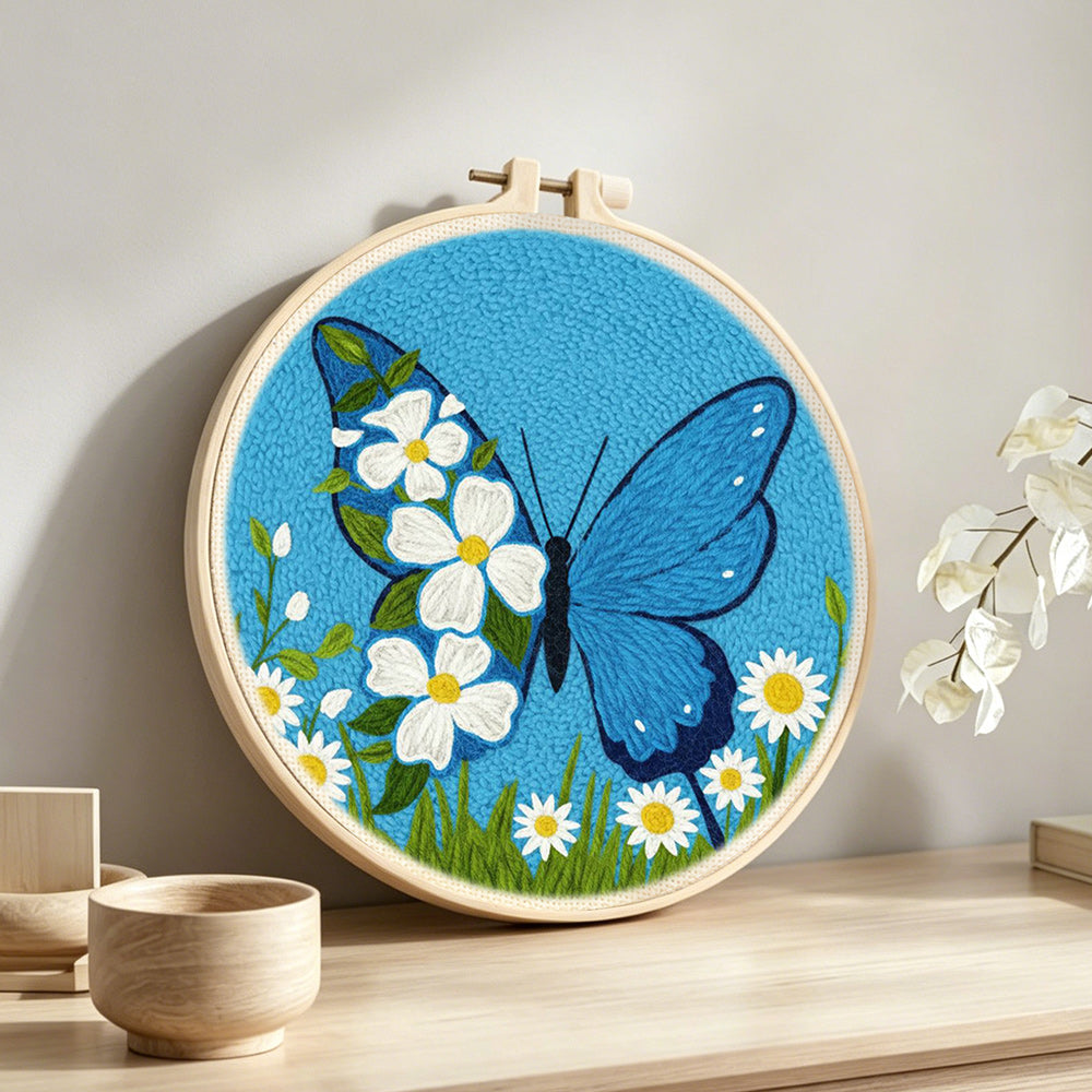 Blue butterfly and white daisies punch needle artwork displayed on a table