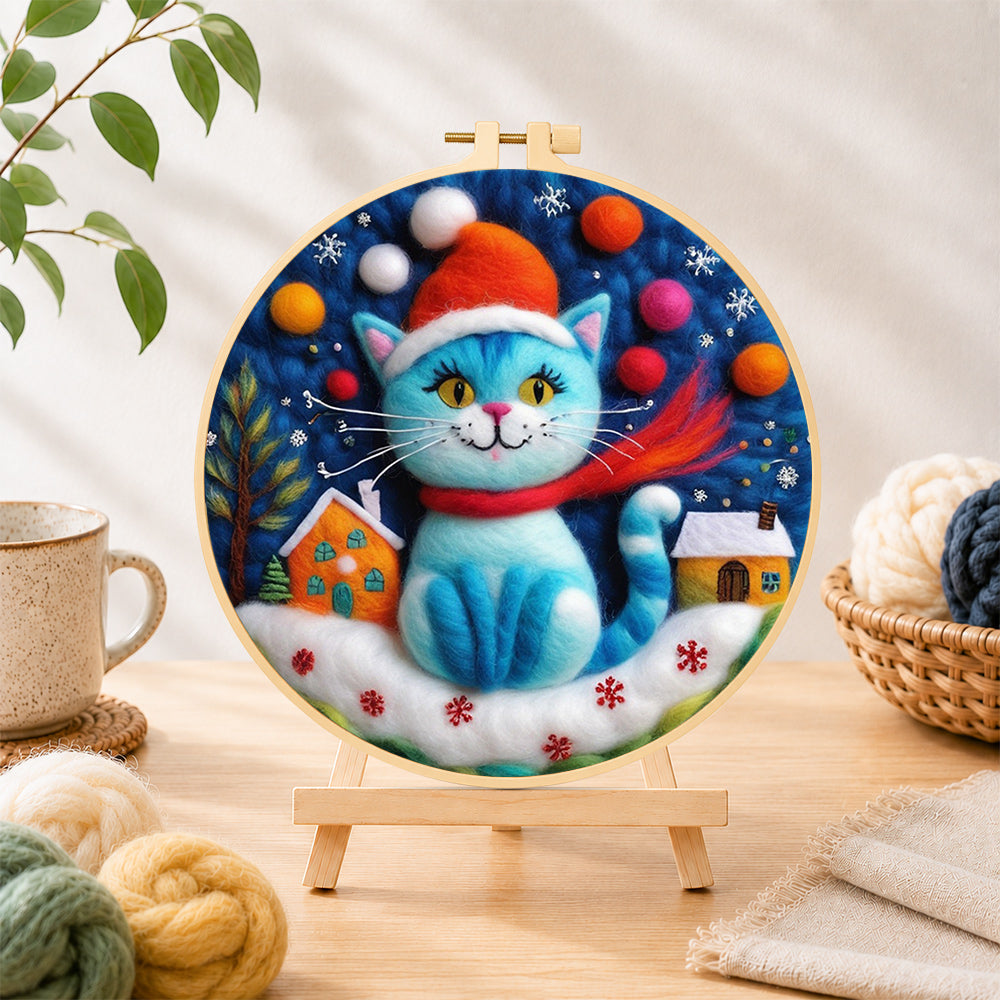 Finished blue christmas cat with houses needle felting displayed on a wooden easel