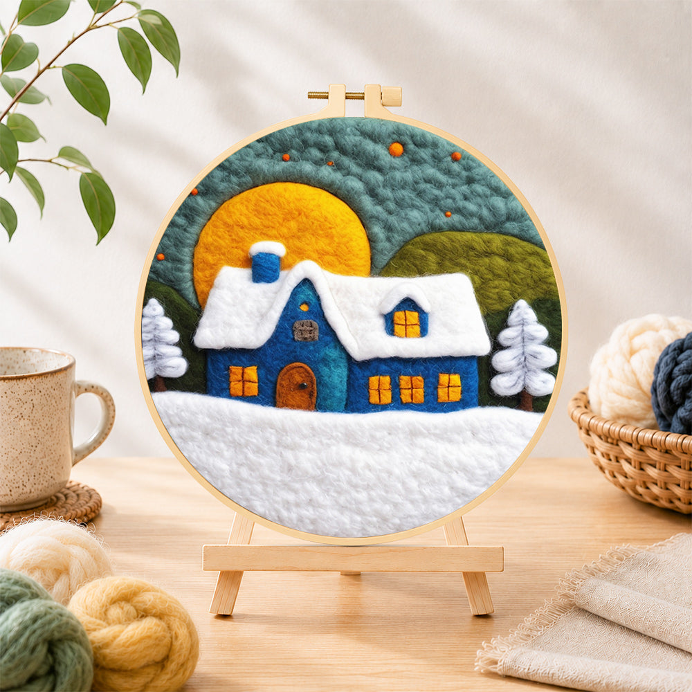 Finished blue cottage under the big yellow moon needle felting displayed on a wooden easel