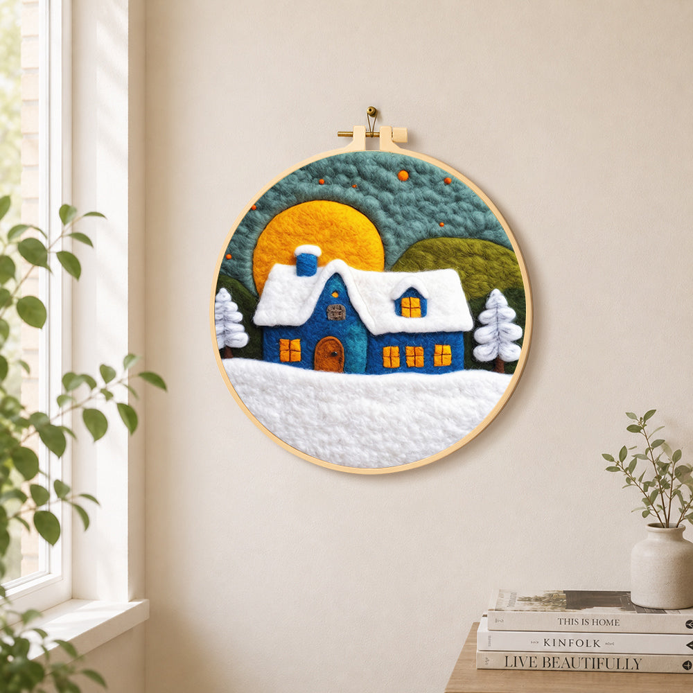 Blue cottage under the big yellow moon needle felt wall art displayed in a bright home interior