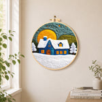 Blue cottage under the big yellow moon needle felt wall art displayed in a bright home interior