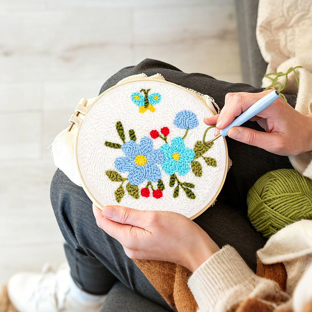Creating handmade blue flowers and little butterfly punch needle artwork