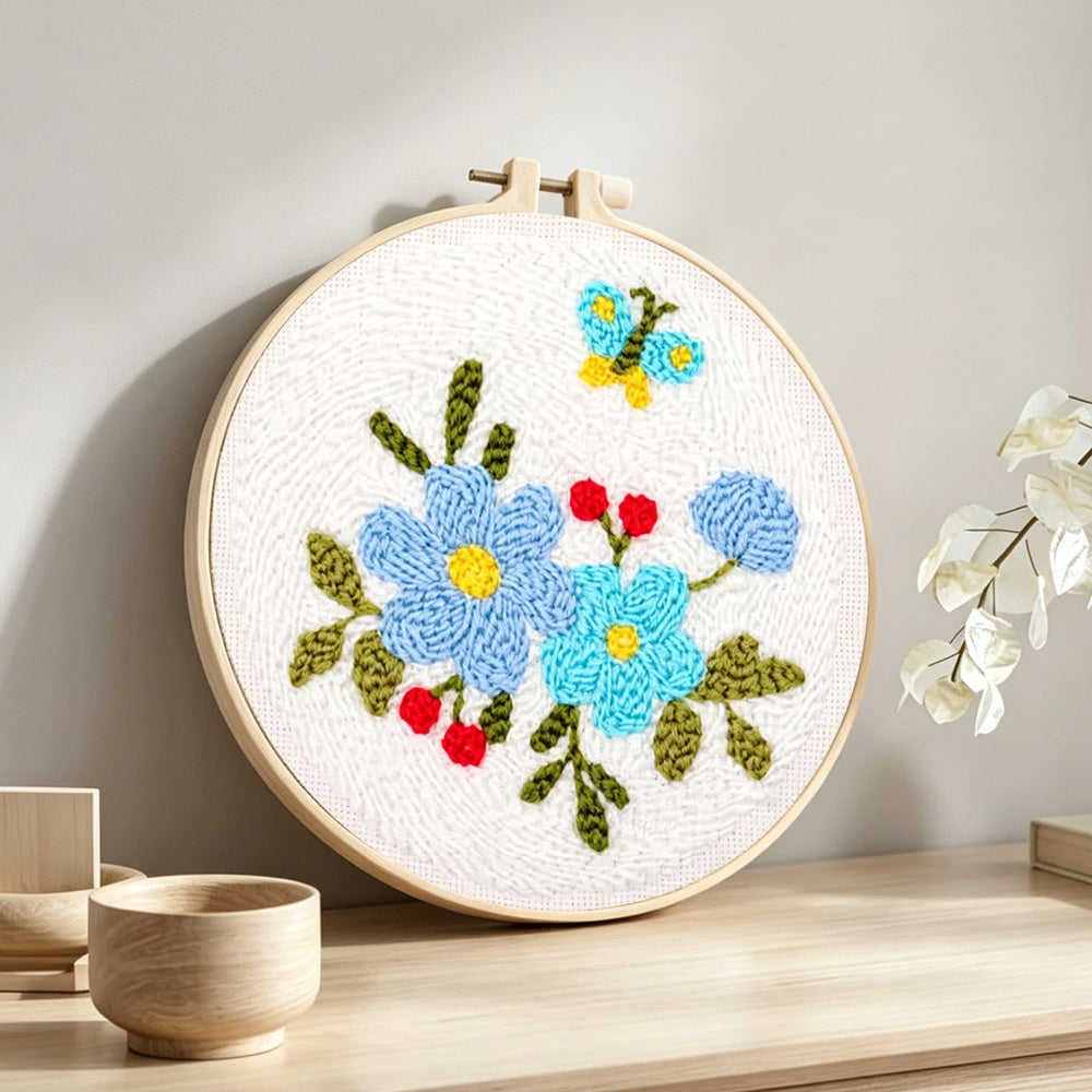 Blue flowers and little butterfly punch needle artwork displayed on a table