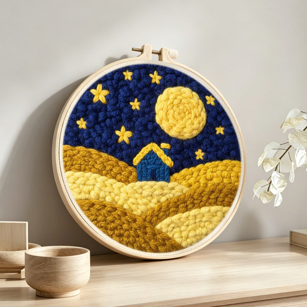 Blue house on yellow hills under the starry sky punch needle artwork displayed on a table