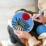 Creating handmade blue sky botanical with red sun punch needle artwork