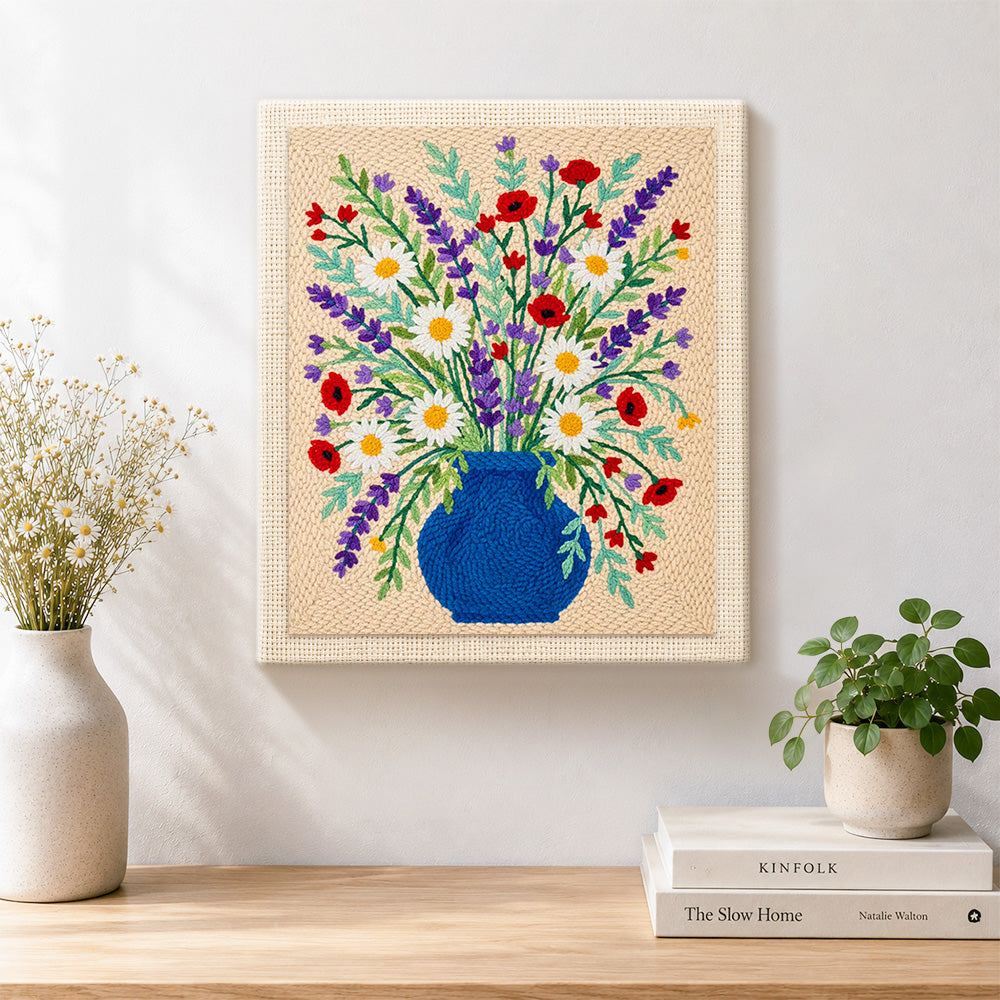 Finished blue vase with lavender, daisies and poppies artwork displayed on a wall