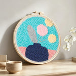 Blue vase with pastel flowers punch needle artwork displayed on a table